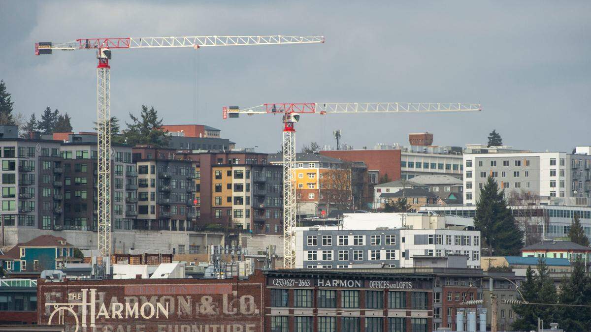 A pair of cranes stand above an apartment building just beginning construction while surrounded by a number of apartment buildings near Tacoma Avenue on Wednesday, Feb. 16, 2022, in Tacoma, Wash.