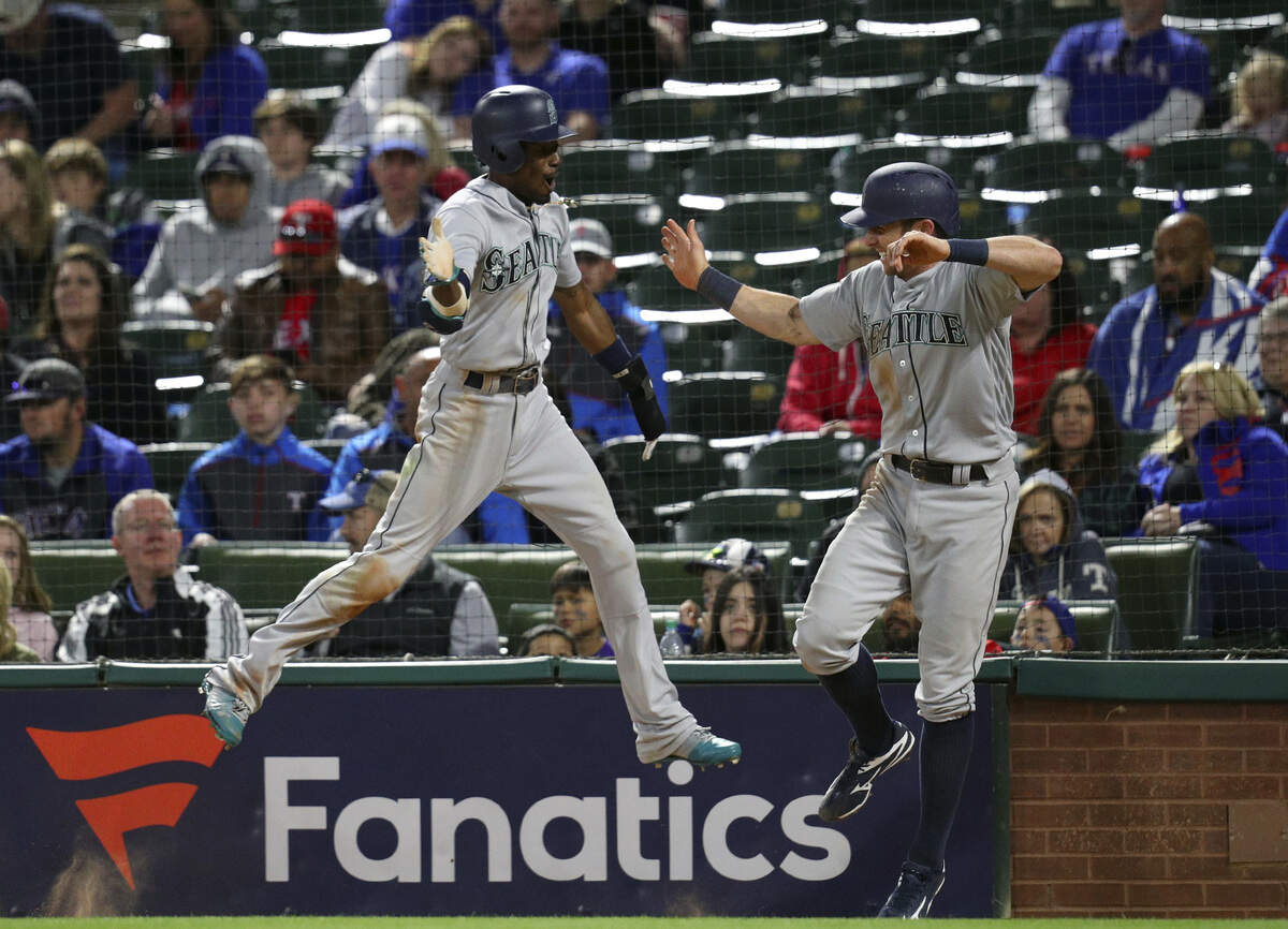 Seattle Mariners Dee Gordon, left, and Andrew Romine (7) celebrate after scoring on a double by Jean Segura during the ninth inning of a baseball game against the Texas Rangers on Friday, April 20, 2018, in Arlington, Texas. (AP Photo/Richard W. Rodriguez)