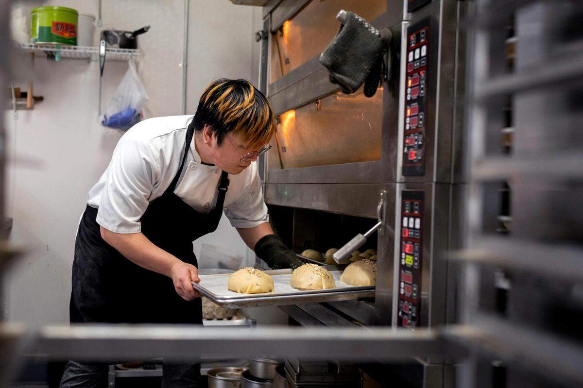 Sous chef David Lee places a tray of mocha bread, a crusty Korean milk bread, in the oven at Bon Bon Bakery on Thursday May 26, 2022. He arrives around 5:30 a.m. every morning begin filling and baking.