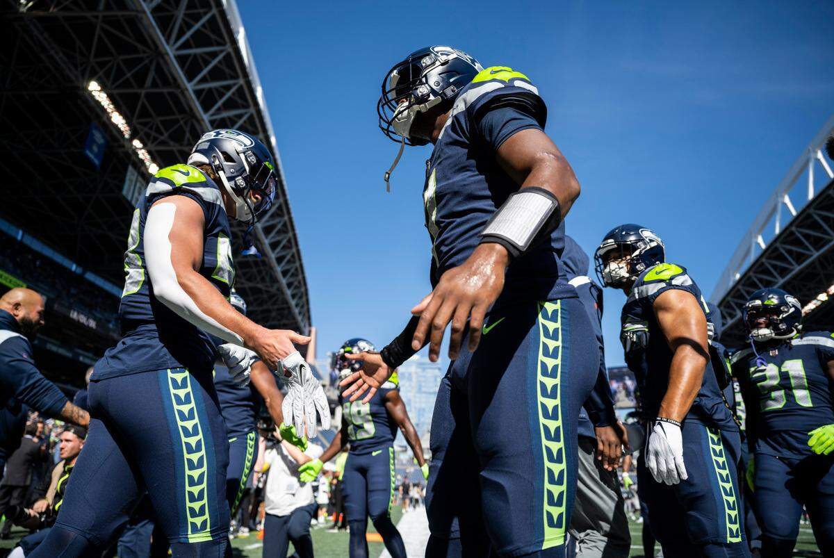 Seattle Seahawks quarterback Geno Smith (7) high-fives Seattle Seahawks linebacker Tanner Muse (58) as they run onto the field to warm up before the start of an NFL game at Lumen Field in Seattle, Wash. on Sept. 25, 2022.