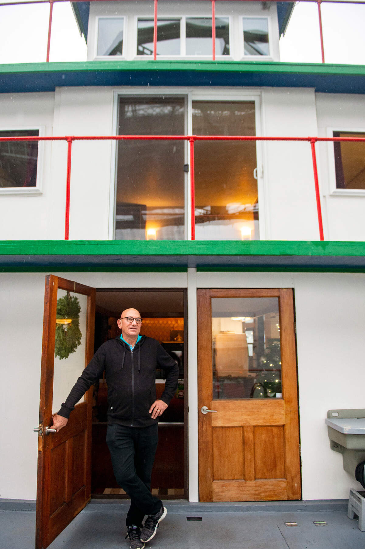Dennis Redmon stands at the front door of his home, a 70-foot ferry called the Annabelle, docked along the pier in the Foss Waterway near downtown Tacoma.