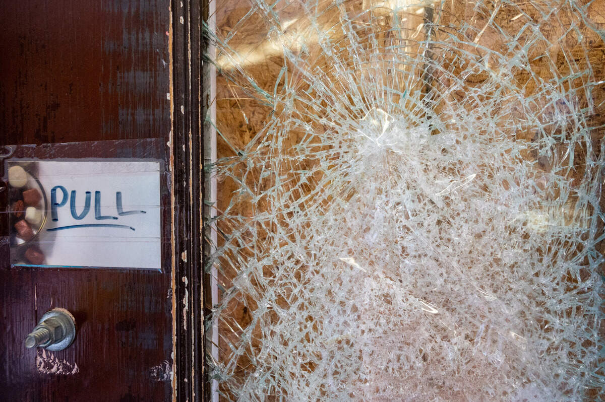 A cracked window in the front door at Johnson Candy Co. is covered with a piece of plywood on Wednesday, Feb. 9, 2022, in Tacoma.