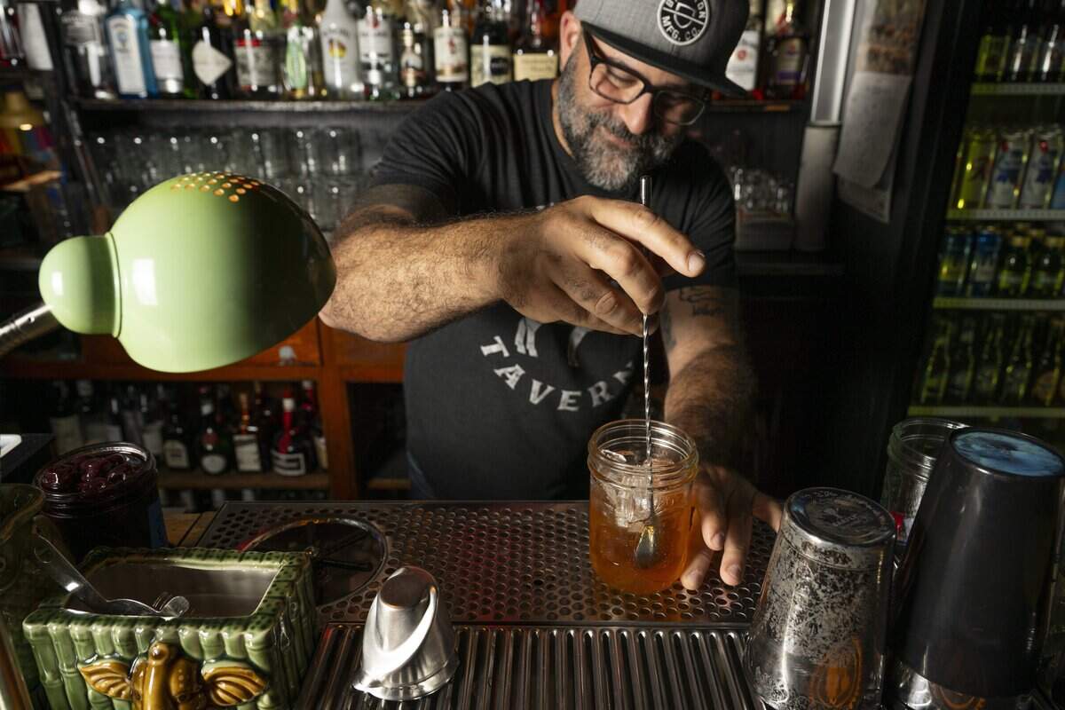 Owner Sam Halhuli stirs an Old Fashioned behind the bar of The Mule Tavern on Wednesday, July 8, 2026, in Tacoma, Wash.