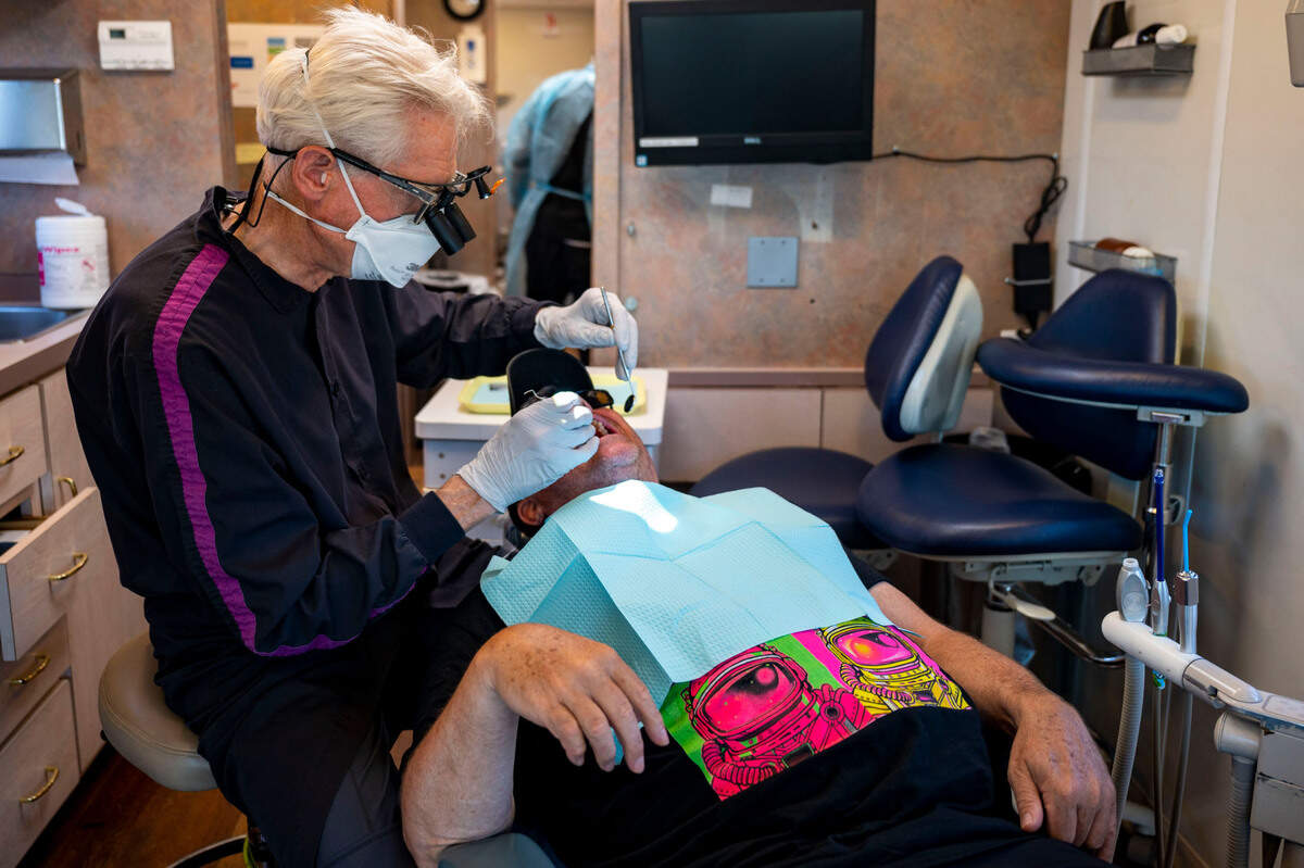 Dr. Steve Urback, of Edgewood, looks at a problematic molar in the mouth of Sjon Scarborough, of Sumner, during a free visit to the mobile dental clinic offered by the Medical Teams International at the Sumner Community Food Bank on Thursday, Aug. 25, 2022, in Sumner, Wash.