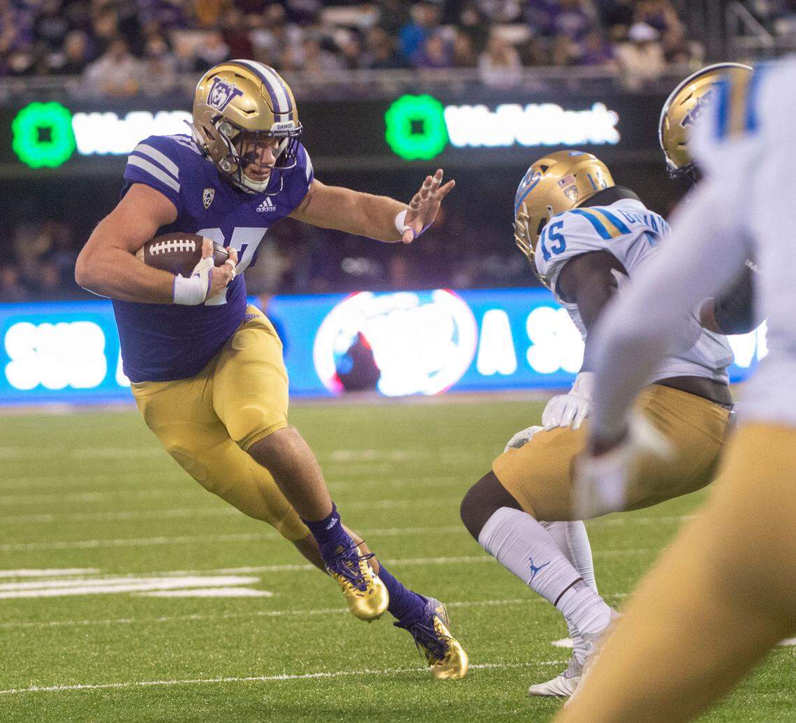 Uw tight end Cade Otton fends off a Bruin during an NCAA college football game between Washington and UCLA Saturday, Oct. 16, 2021, in Seattle.
