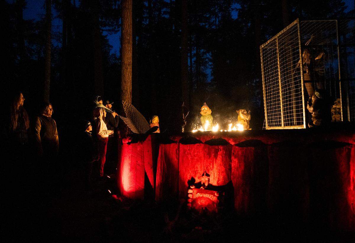 A group stops to watch an animatronic display as they walk along the mile long trail at My Haunted Forest at Grand Farms in Vaughn, Wash. on Oct. 23, 2022.