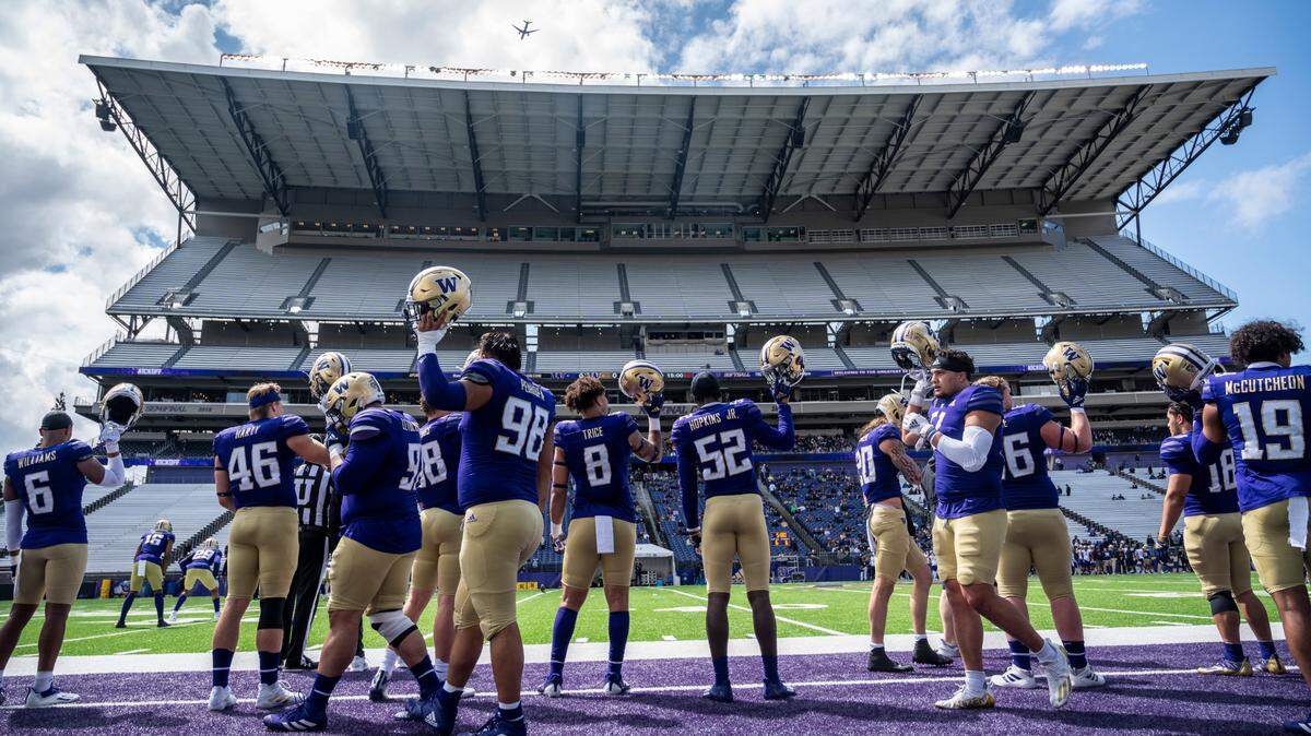 University of Washington Huskies players raise their helmets at the start of the spring game at Husky Stadium in Seattle, Wash. on Saturday, April 30, 2022.