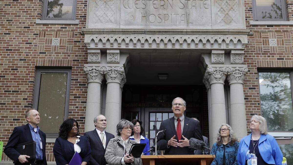 Washington Gov. Jay Inslee, third from right, speaks Friday, May 11, 2018, in front of Western State Hospital in Lakewood, Wash.