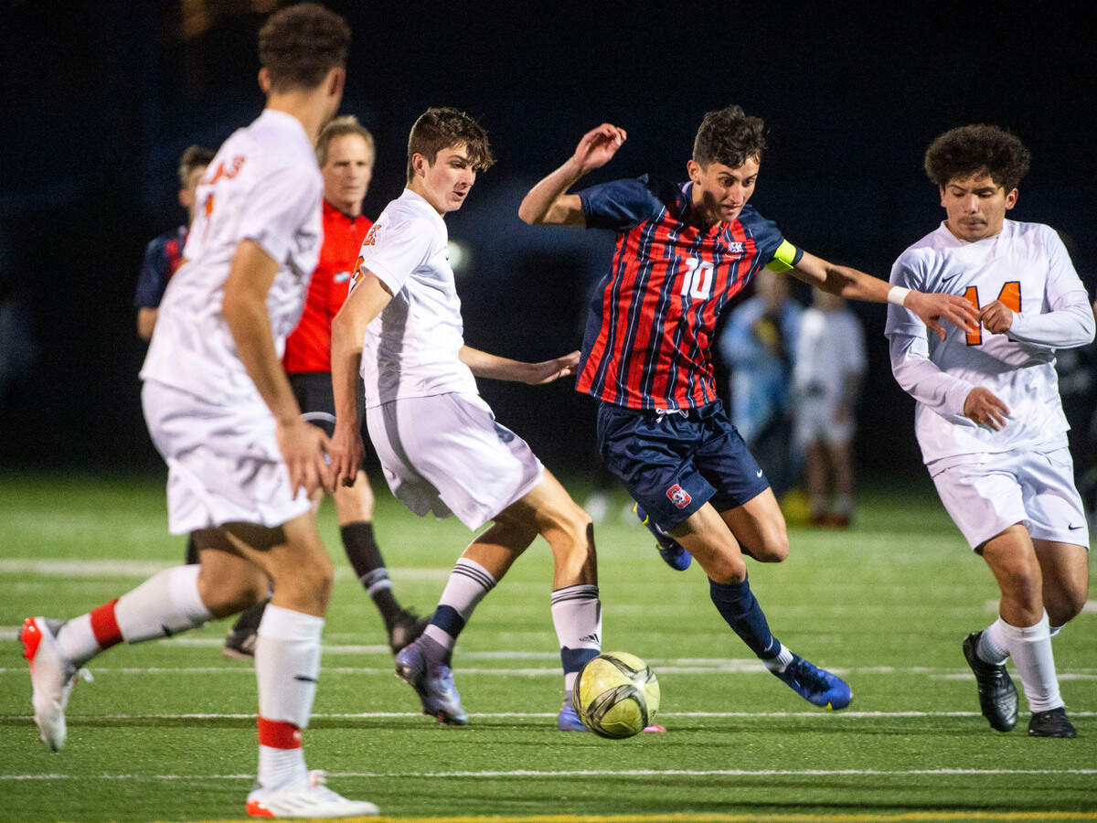 Silas midfielder Connor Tollan dribbles through a pair of Lakes defenders before being fouled during the second half of a Pierce County League game on Thursday, March 31, 2022, at Silas High School in Tacoma, Wash.
