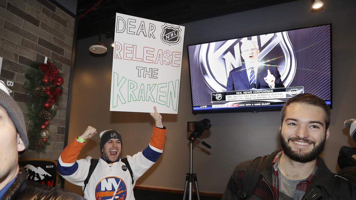 Max Rubin cheers and holds a sign in favor of the team name “Kraken” following the announcement of a new NHL hockey team in Seattle, at a celebratory party Tuesday, Dec. 4, 2018, in Seattle. (AP Photo/Elaine Thompson)