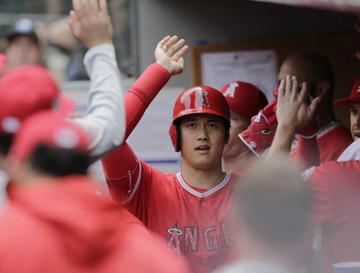Los Angeles Angels' Shohei Ohtani is congratulated in the dugout after scoring against the Seattle Mariners during the second inning of a baseball game, Wednesday, July 4, 2018, in Seattle. (AP Photo/John Froschauer)