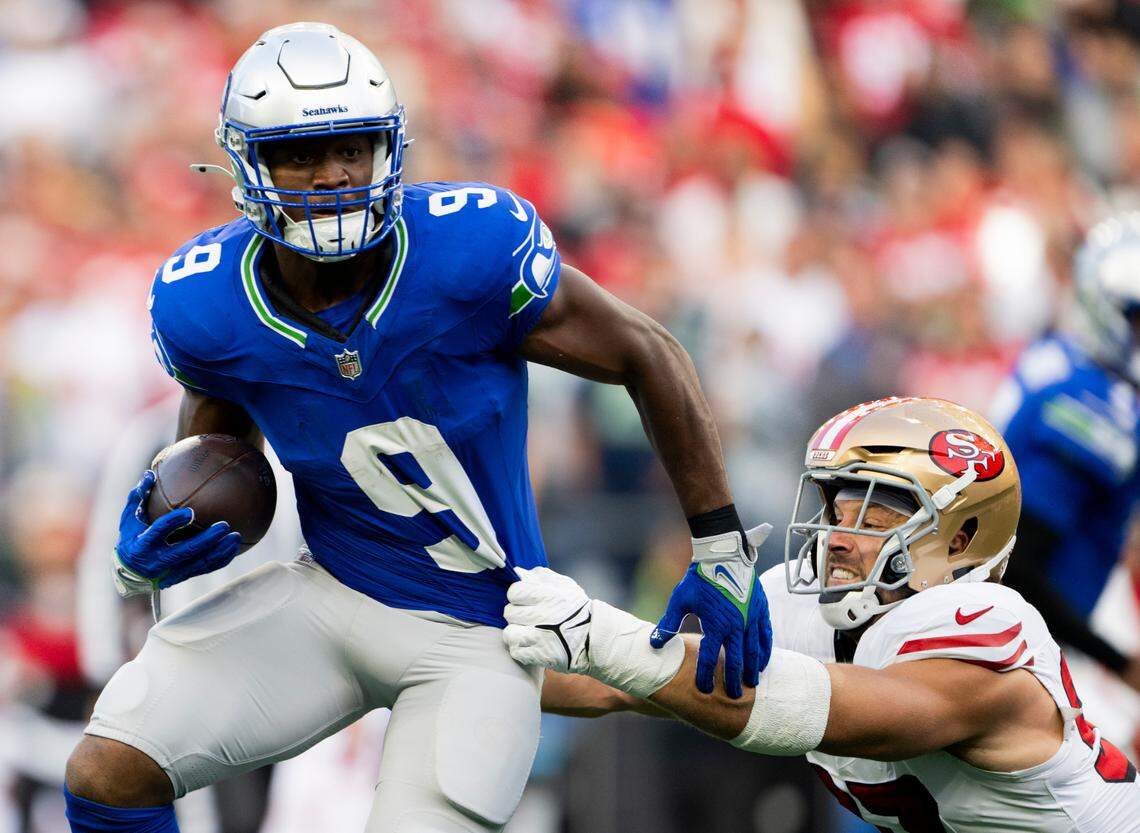 Seattle Seahawks running back Kenneth Walker III (9) picks up yard as San Francisco 49ers defensive end Nick Bosa (97) hangs on during the first quarter of the game at Lumen Field, on Thursday, Oct. 10, 2024, in Seattle, Wash.