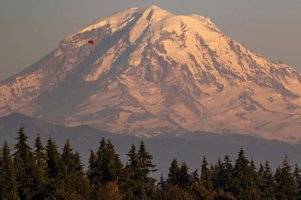 A skydiver floats to the ground in a parachute in front of Mount Rainier near Bonney Lake on July 26, 2022.