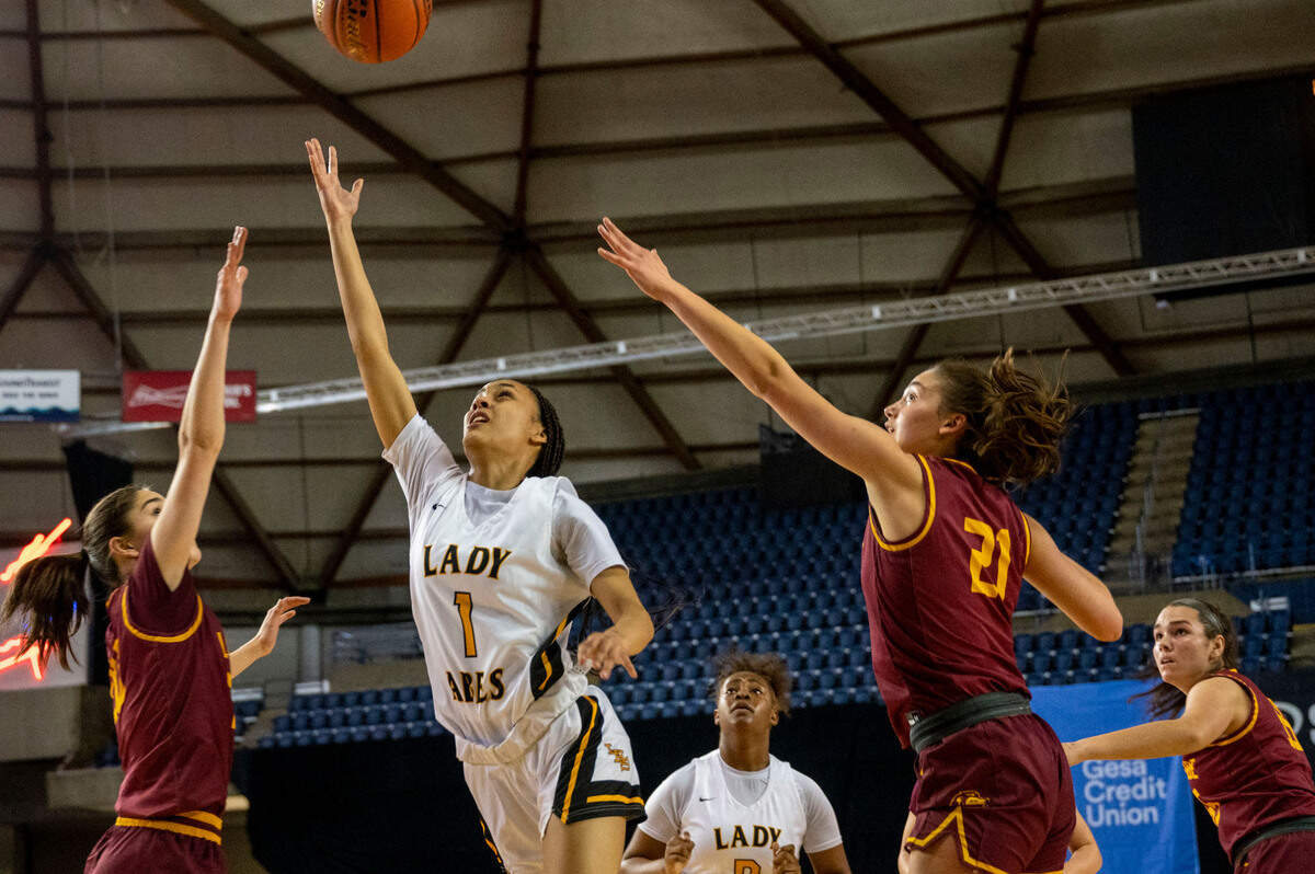 Lincoln guard Ciona Wells (1) floats up a shot in between a pair of Lakeside defenders during the first quarter of a Class 3A state tournament game on Wednesday, March 2, 2022, at the Tacoma Dome, in Tacoma, Wash.