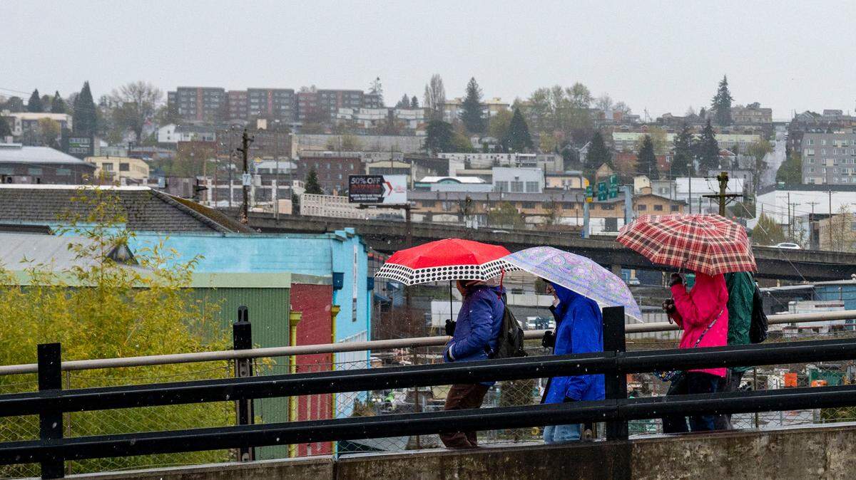 Umbrella-clad pedestrians walk along East D Street through a spat of sleet on Thursday, April 14, 2022, in Tacoma, Wash.