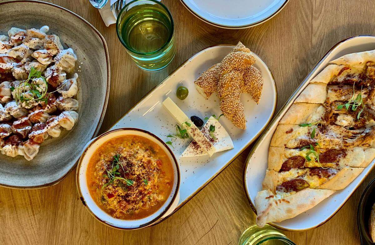 A go-to spread at Lezzet Brunch, from left: handmade beef manti in tomato sauce, menemen served with simit and cheese, combo pide with sucuk on one side and spiced, slow-cooked chicken on the other.