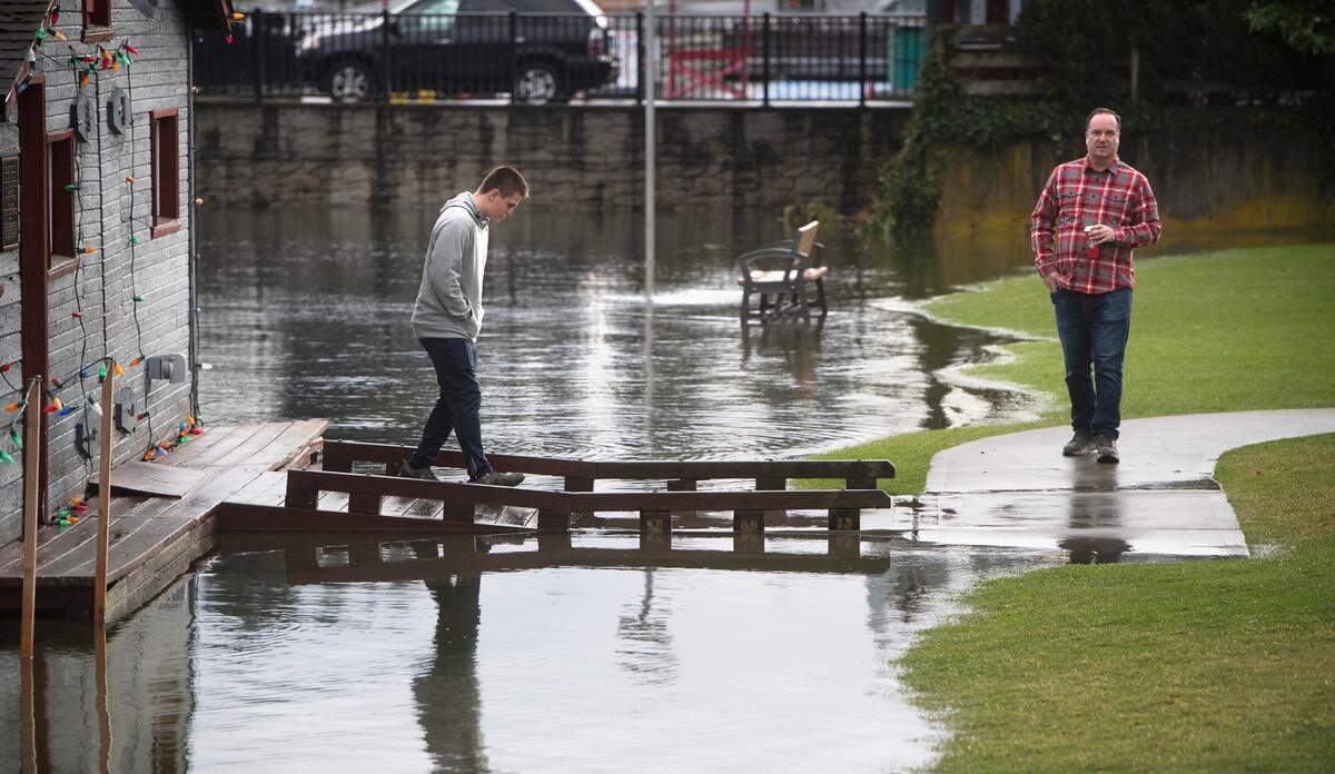 Taylor Gore and his dad, Michael Gore of Gig Harbor, check out the high-tide floodwaters at Skansie Brothers Park and Netshed along the waterfront in Gig Harbor, Washington, on Tuesday, Dec. 27, 2022.