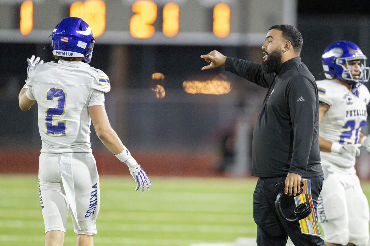 Puyallup head coach DJ Mims, right, talks to players on the field as they play Emerald Ridge on Friday, Sept. 26, 2025, in Puyallup.