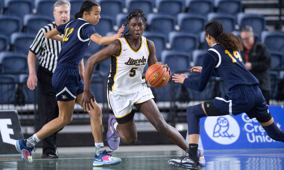 Lincoln’s Oliviyah Edwards pushes the ball up court between Everett defenders Alana Washington (left) and Mae Washington during their opening-round game at the WIAA state basketball tournament in the Tacoma Dome in Tacoma, Washington, on Wednesday, March 1, 2023. Lincoln won the game, 45-43.