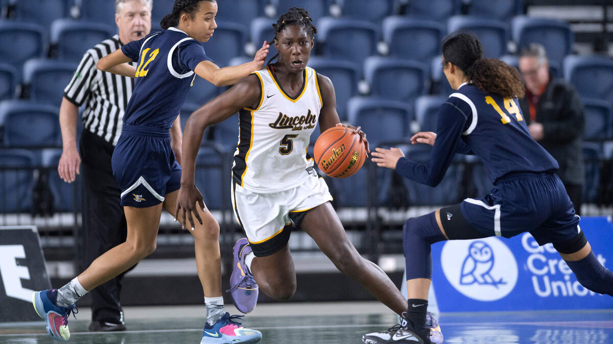 Lincoln’s Oliviyah Edwards pushes the ball up court between Everett defenders Alana Washington (left) and Mae Washington during their opening-round game at the WIAA state basketball tournament in the Tacoma Dome in Tacoma, Washington, on Wednesday, March 1, 2023. Lincoln won the game, 45-43.
