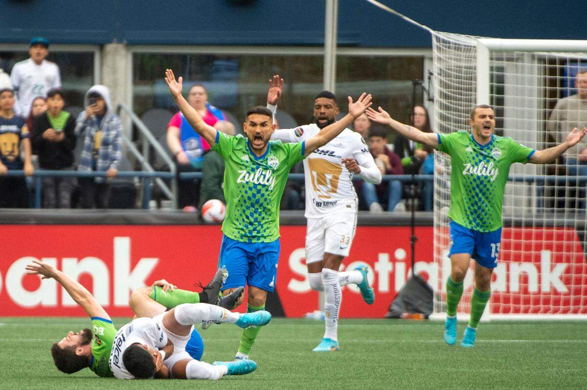 Seattle Sounders midfielder Cristian Roldan (7) raises his hands in anger after Pumas midfielder Leonel López (17) and midfielder João Paulo Mior (6) collided while fighting for a ball during the first half of the second leg of the CONCACAF Champions League Final at Lumen Field in Seattle, on Wednesday, May 4, 2022.