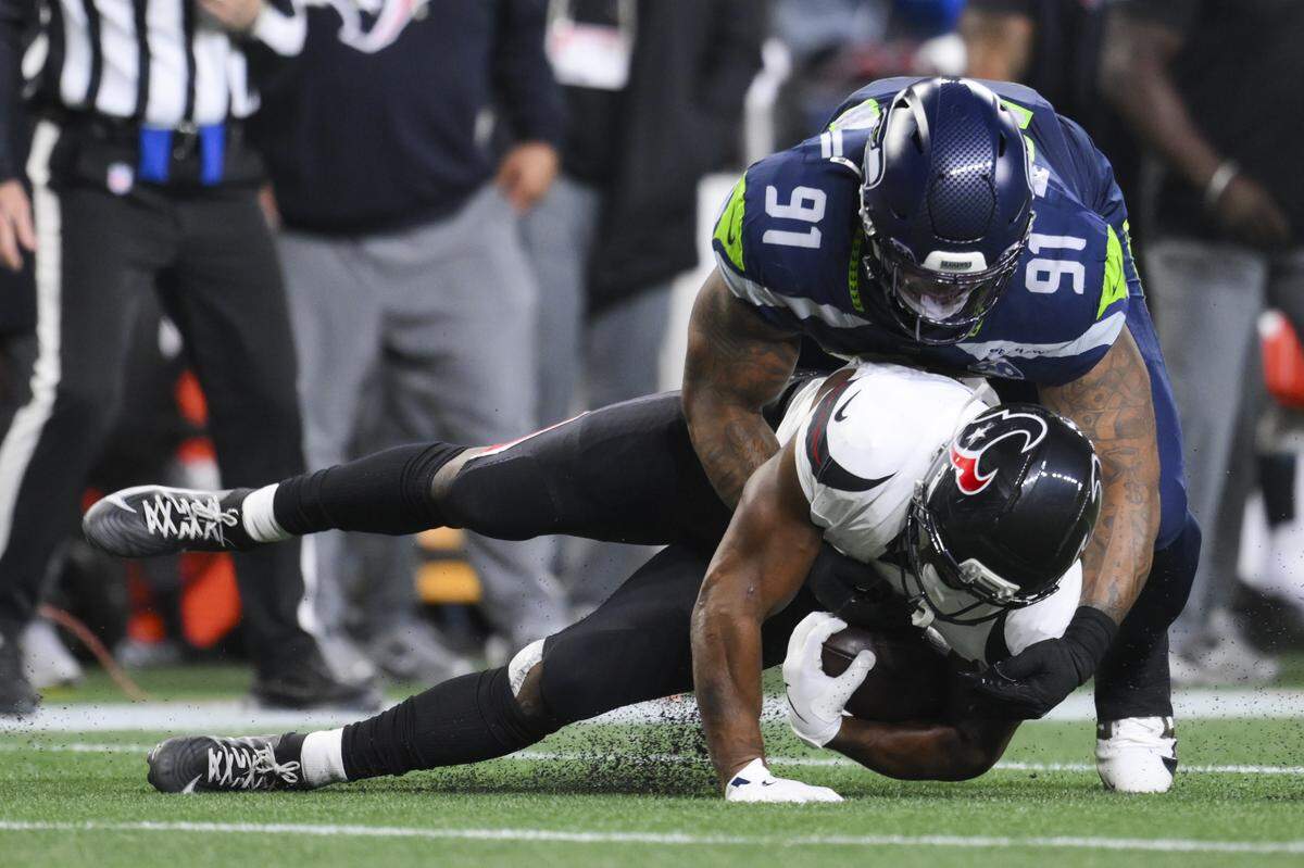 Seattle Seahawks defensive tackle Byron Murphy II (91) tackles Houston Texans running back Nick Chubb (21) for a 5-yard loss during the second quarter of the game at Lumen Field, on Monday, Oct. 20, 2025, in Seattle.