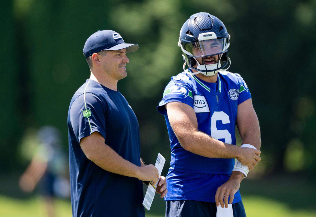 Seahawks head coach Mike MacDonald and quarterback Sam Howell (6) talk during the first day of training camp at the Virginia Mason Athletic Center, Wednesday, July 24, 2024, in Renton.