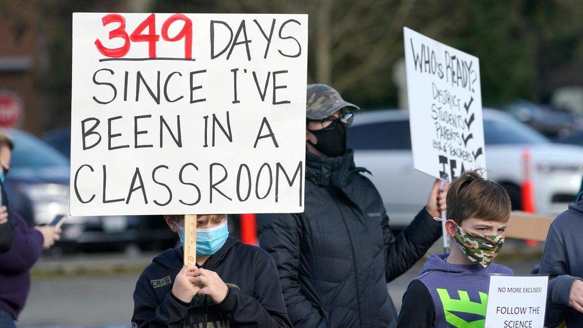 Students hold signs as they take part in a rally to encourage wider opening of in-person learning in the Issaquah School District, Wednesday, Feb. 24, 2021, in Issaquah, Wash., east of Seattle. Students in kindergarten and lower-elementary grades in the district recently returned to school under a hybrid in-person learning program, but older elementary, middle-, and high school students are still being taught remotely. (AP Photo/Ted S. Warren