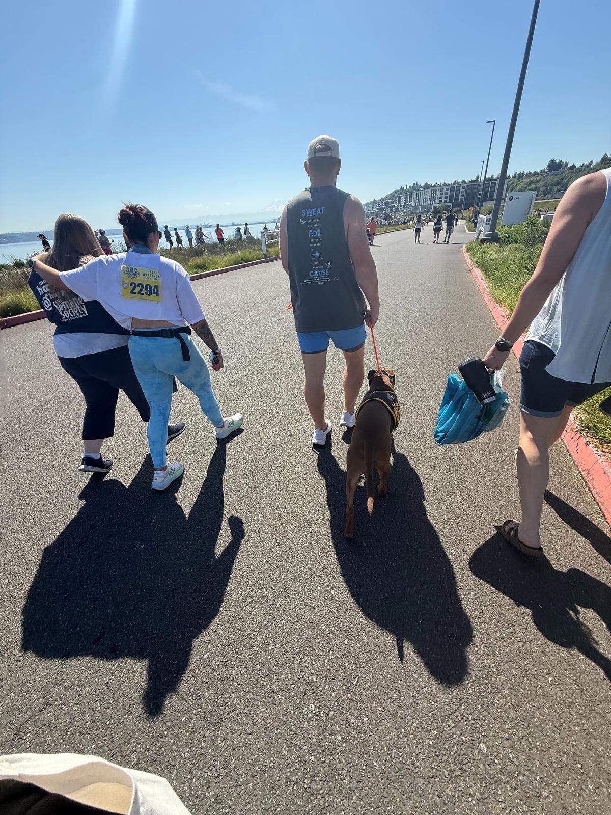 Alexis Drugge, second to left, consoles a Humane Society volunteer while Drugge’s fiancé, Mark Symmons, walks a dog named Dallas following a deadly dog-on-dog attack at the Tacoma City Marathon on Sunday, May 3, 2026.