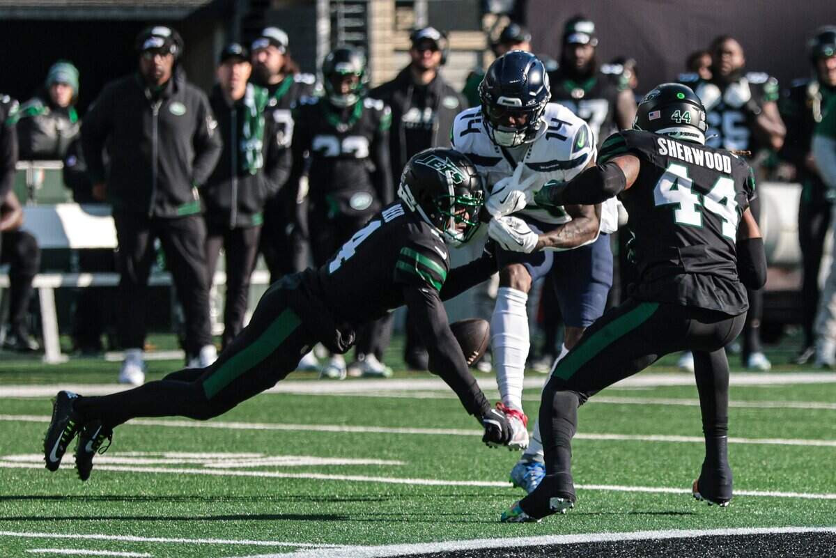 Dec 1, 2024; East Rutherford, New Jersey, USA; New York Jets cornerback D.J. Reed (4) breaks up a pass intended for Seattle Seahawks wide receiver DK Metcalf (14) in front of linebacker Jamien Sherwood (44) during the first quarter at MetLife Stadium. Mandatory Credit: Vincent Carchietta-Imagn Images