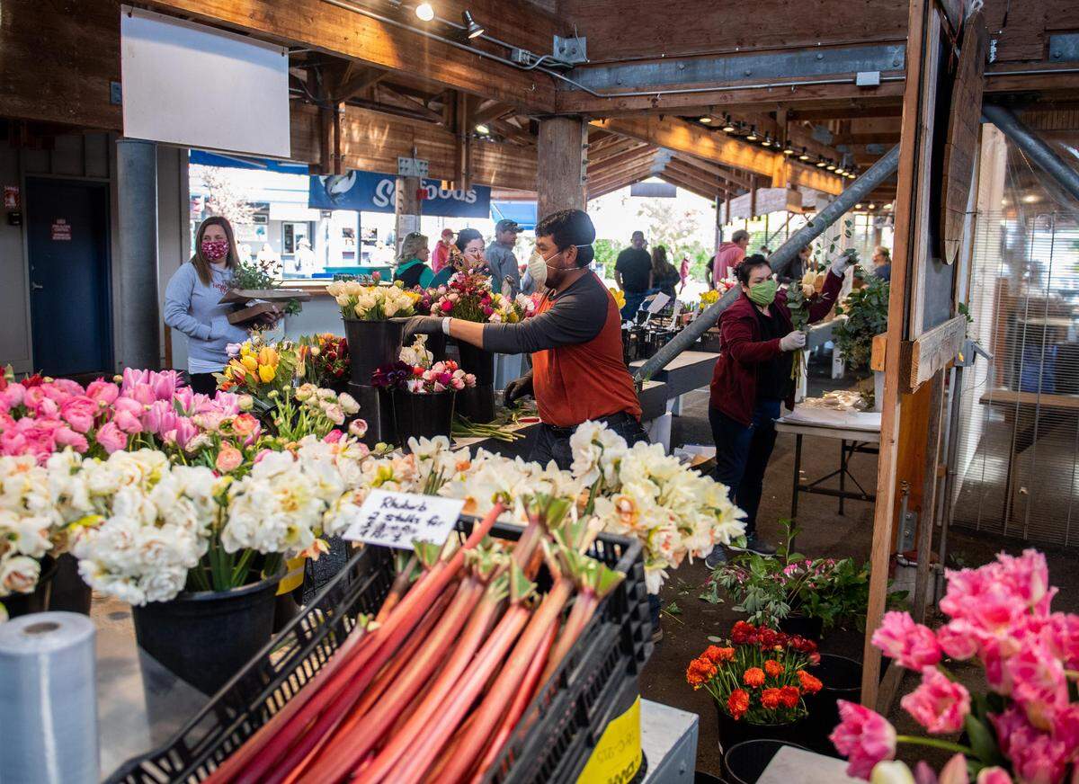 People buy flowers from a stand at the Olympia Farmers Market in Olympia in 2020.
