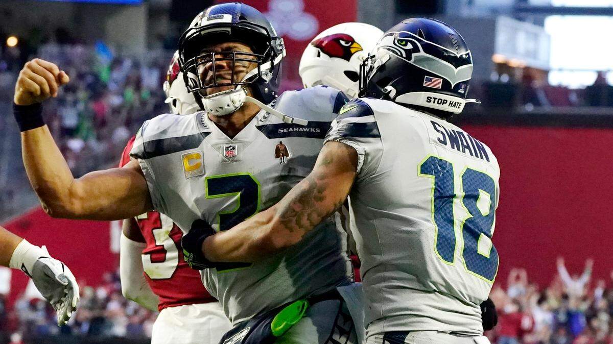 Seattle Seahawks quarterback Russell Wilson, left, celebrates his touchdown run against the Arizona Cardinals with Seattle Seahawks wide receiver Freddie Swain (18) during the second half of an NFL football game Sunday, Jan. 9, 2022, in Glendale, Ariz. (AP Photo/Darryl Webb)