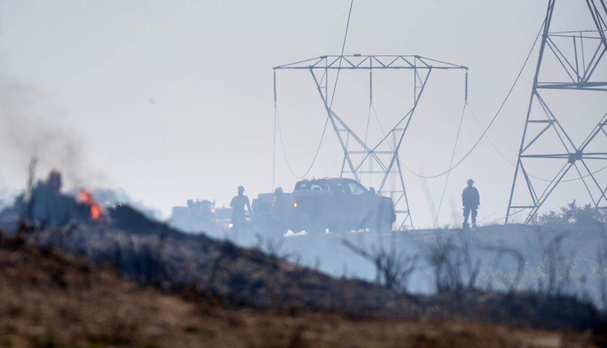 Fire crews keep watch over a wildfire beneath the high tension power lines along 82nd Avenue South in Roy, Washington, on Thursday, July 6, 2023.