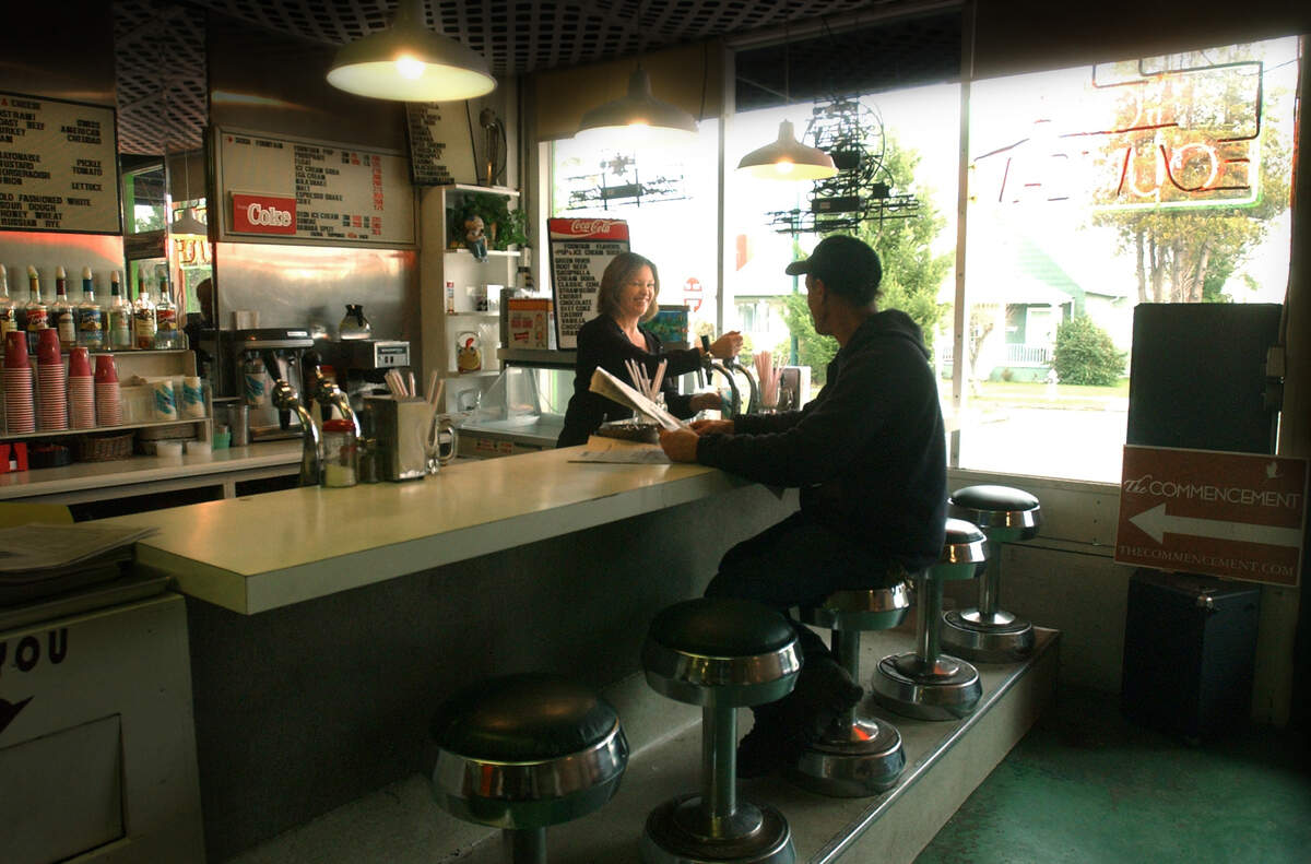 Beth Torbet, co-owner of Don’s Ruston Market in Ruston, serving a drink to a customer in an old soda fountain setting at the Don’s Ruston Market.