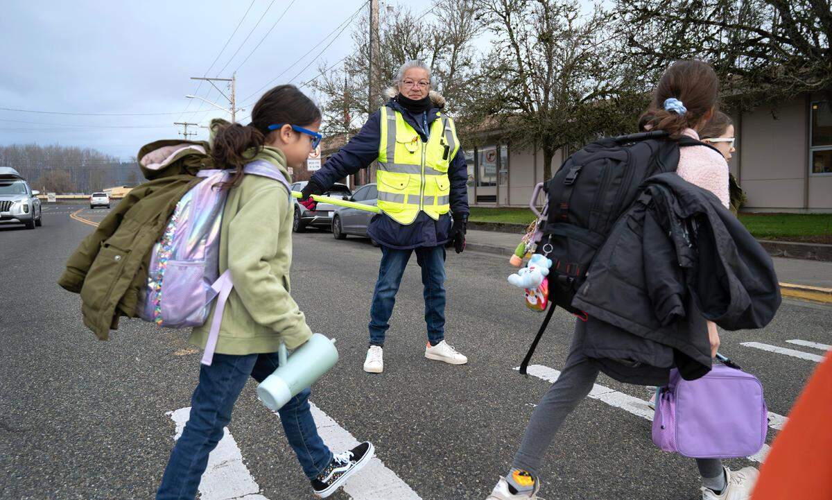 Paraeducator Judy Dennison guards the street as students arrive at Spinning Elementary School in Puyallup, Washington, on Thursday, Jan. 30, 2025. A proposed $800 million bond for the Puyallup School District would include building a new school further away from the busy roadways and train tracks.