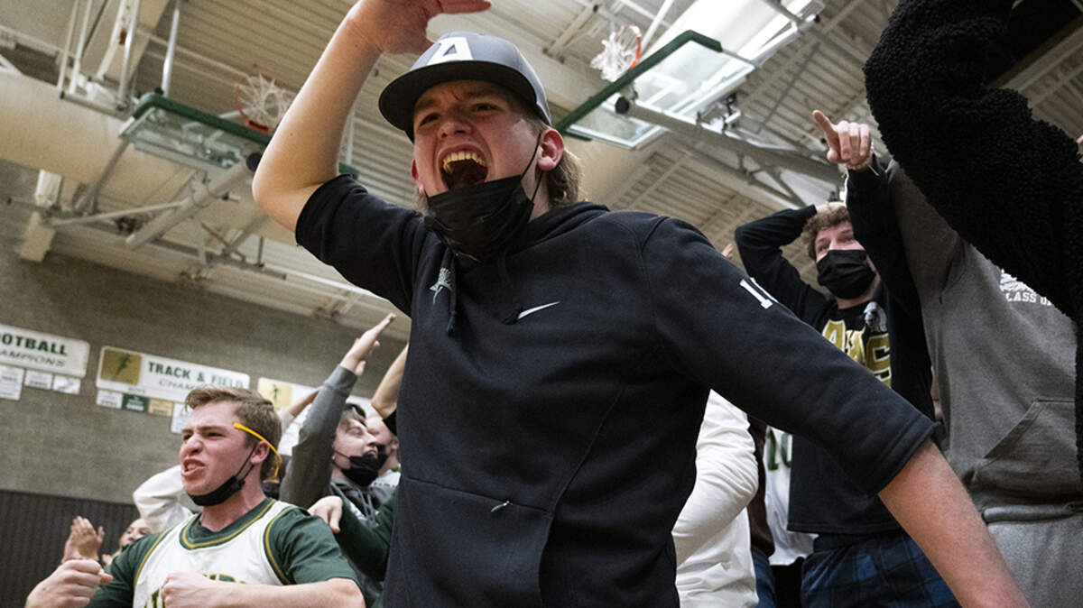 Auburn High School junior Carson McCreery, center, and senior Joel Casperson, left, cheer from the stands during a District 3/4 boys basketball tournament opening round game at Auburn High School on Saturday, Feb. 12, 2022, in Auburn, Wash.