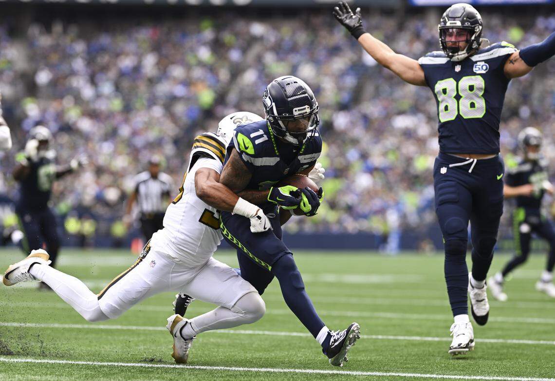 Seattle Seahawks wide receiver Jaxon Smith-Njigba (11) scores a touchdown as New Orleans Saints safety Jonas Sanker (33) hits him during the first quarter of the game at Lumen Field, on Sunday, Sept. 21, 2025 in Seattle.