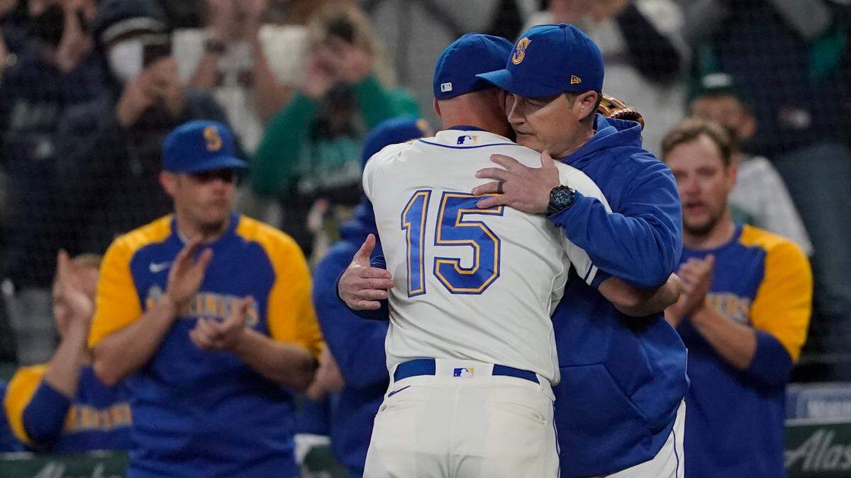 Seattle Mariners third baseman Kyle Seager (15) hugs manager Scott Servais, right, after he was subbed out of a baseball game against the Los Angeles Angels during the ninth inning, Sunday, Oct. 3, 2021, in Seattle. (AP Photo/Ted S. Warren)