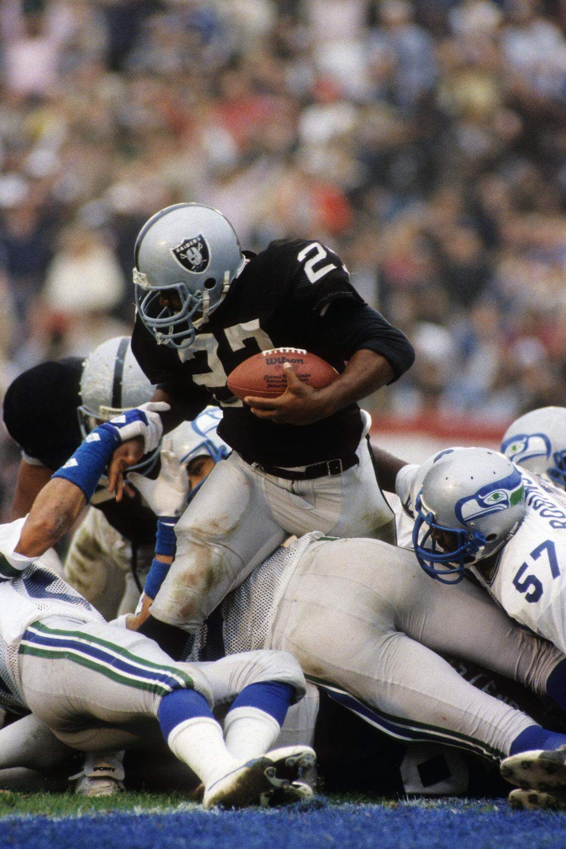 LOS ANGELES - JANUARY 8:  Running back Frank Hawkins #27 of the Los Angeles Raiders battles for extra yards against the Seattle Seahawks defense during the 1983 AFC Conference Championship game at the Los Angeles Memorial Coliseum on January 8, 1984 in Los Angeles, California.  The Raiders won 30-14. (Photo by George Rose/Getty Images) 