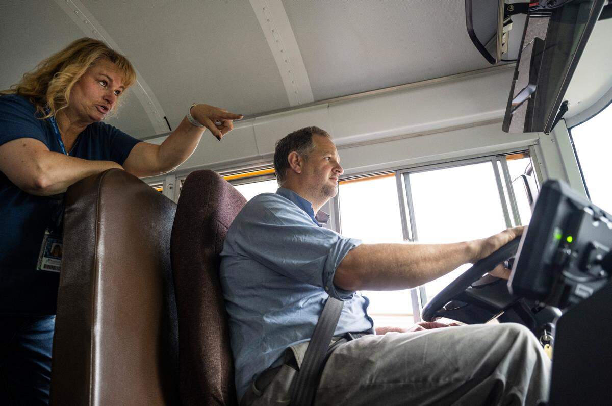 Peninsula School District bus driver Kristie Matthews, left, trains Roland Checketts on how to drive a school bus at a bus driver hiring event hosted by the district in the parking lot behind Purdy Elementary in Key Peninsula, Wash. on August 26, 2022.