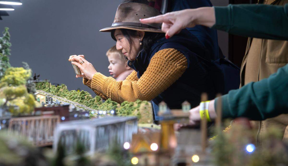 Hisano Rowland of Auburn snaps a photo of the detailed landscapes on display during the 28th Annual Model Train Festival at the Washington State History Museum in Tacoma, Washington, on Friday, Dec. 27, 2024. The Model Train Festival continues through January 1.