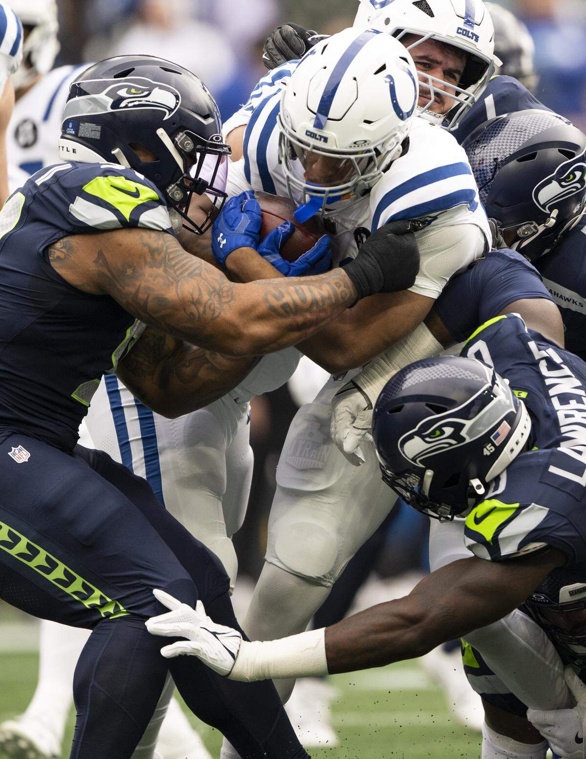 Indianapolis Colts running back Jonathan Taylor (28) is stopped by Seattle Seahawks defensive end Demarcus Lawrence (0) and defensive tackle Byron Murphy II (91) during the first quarter of the game at Lumen Field, on Sunday, Dec. 14, 2025, in Seattle.