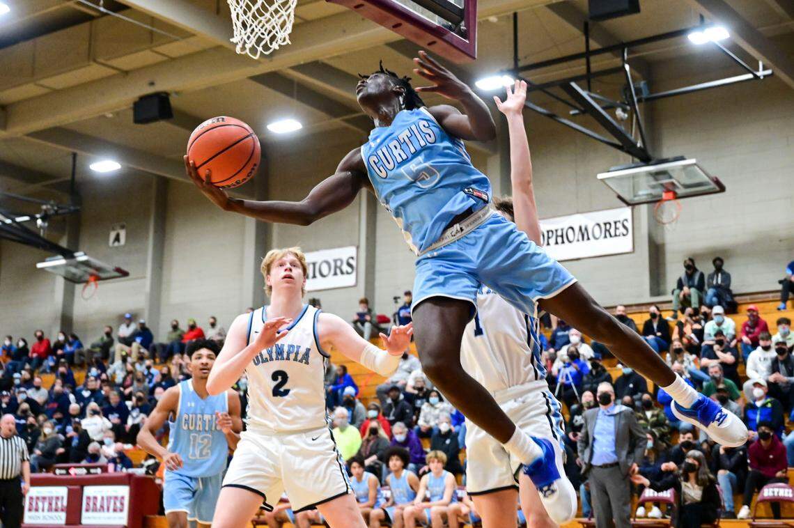 Curtis guard Zoom Diallo (5) attempts a reverse layup as Olympia guard Caden Roth (1) and forward Andreas Engholm (2) defend during the fourth quarter of a 4A South Puget Sound League tournament championship game on Saturday, Feb. 5, 2022, at Bethel High School in Spanaway, Wash.