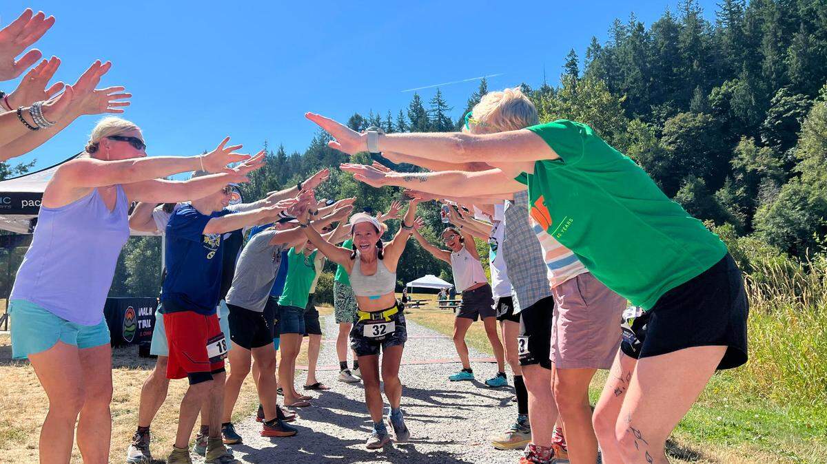 Van Phan, 52, being congratulated after running 100 miles at the Hamster Endurance Runs at Padden Lake, Washington on Aug. 13, 2023.