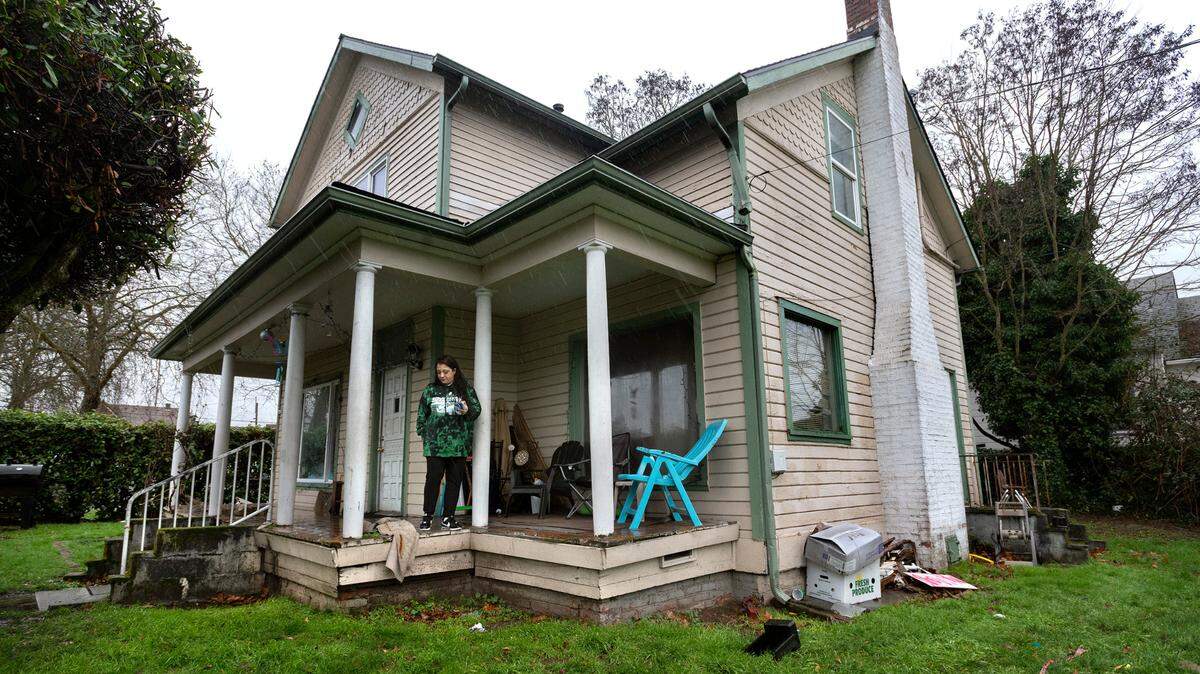 April Mays stands on the front porch of the historic Asberry House where she has lived for the past eight years in the Hilltop neighborhood of Tacoma, Washington, on Thursday, Jan. 6, 2022.