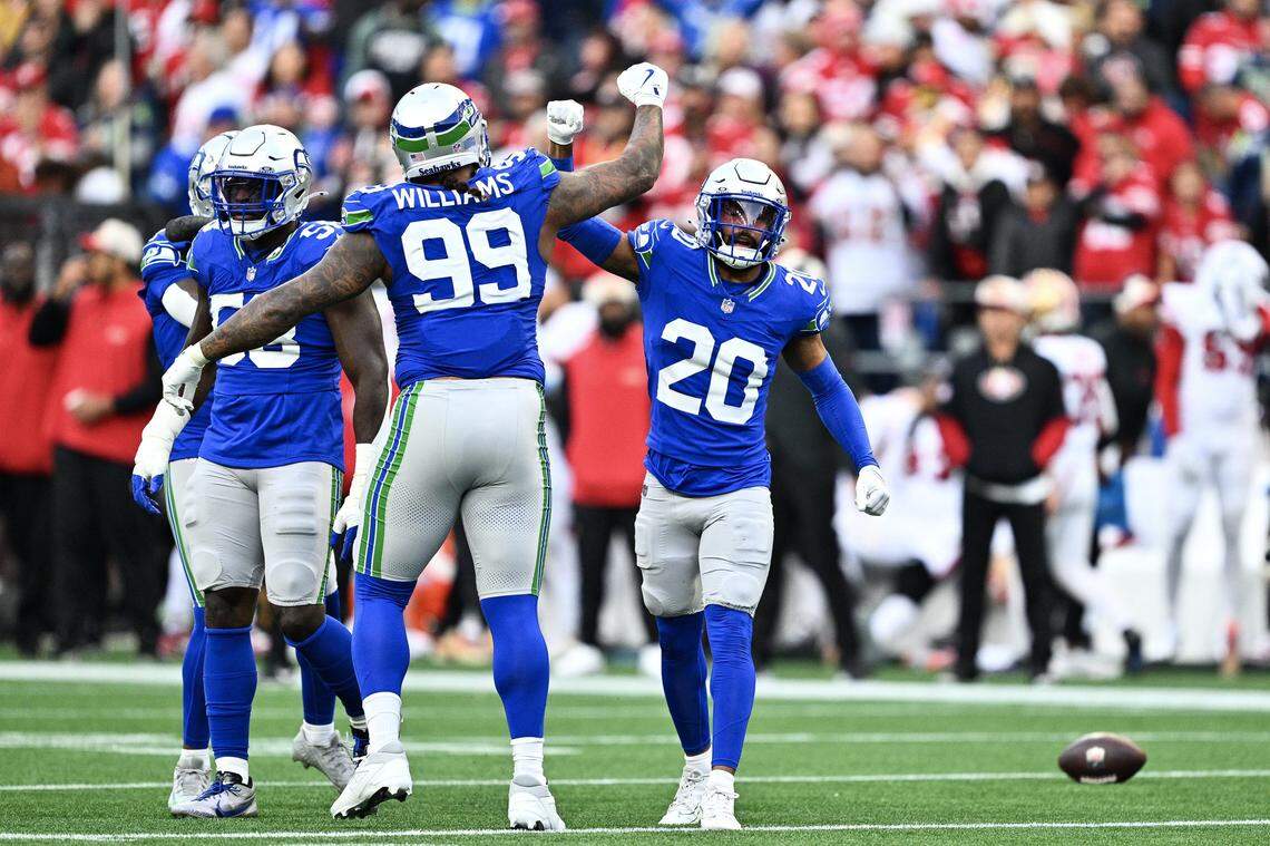SEATTLE, WASHINGTON - OCTOBER 10: Julian Love #20 of the Seattle Seahawks celebrates a defensive stop with Leonard Williams #99 during the first quarter against the San Francisco 49ers at Lumen Field on October 10, 2024 in Seattle, Washington. (Photo by Jane Gershovich/Getty Images)