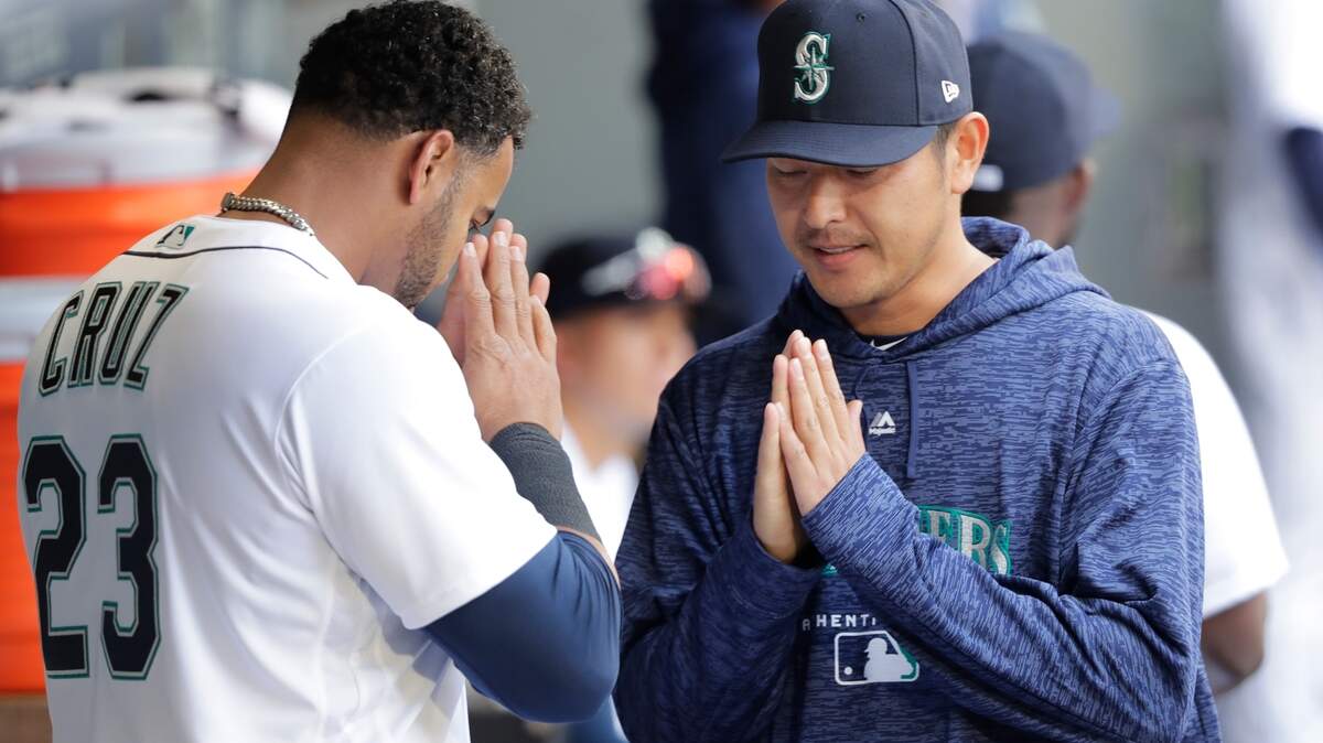 Seattle Mariners pitcher Hisashi Iwakuma, right, greets Nelson Cruz in the dugout before a baseball game against the Cleveland Indians, Saturday, March 31, 2018, in Seattle. (AP Photo/Ted S. Warren)