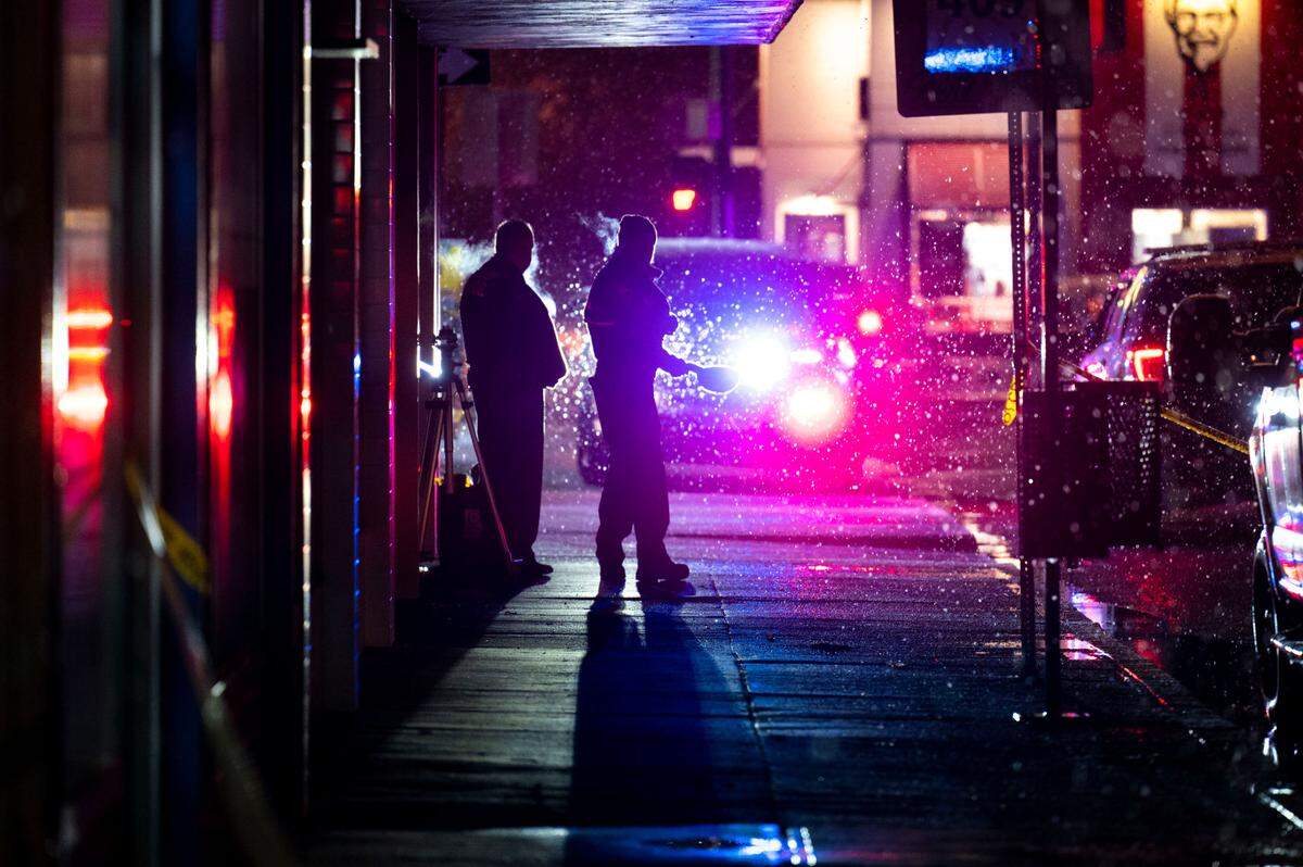 Puyallup Police officers stand in the snow as they canvas the 100 block of East Stewart Avenue after a man was killed inside a barbershop on Wednesday, Nov. 30, 2022, in Puyallup, Wash.