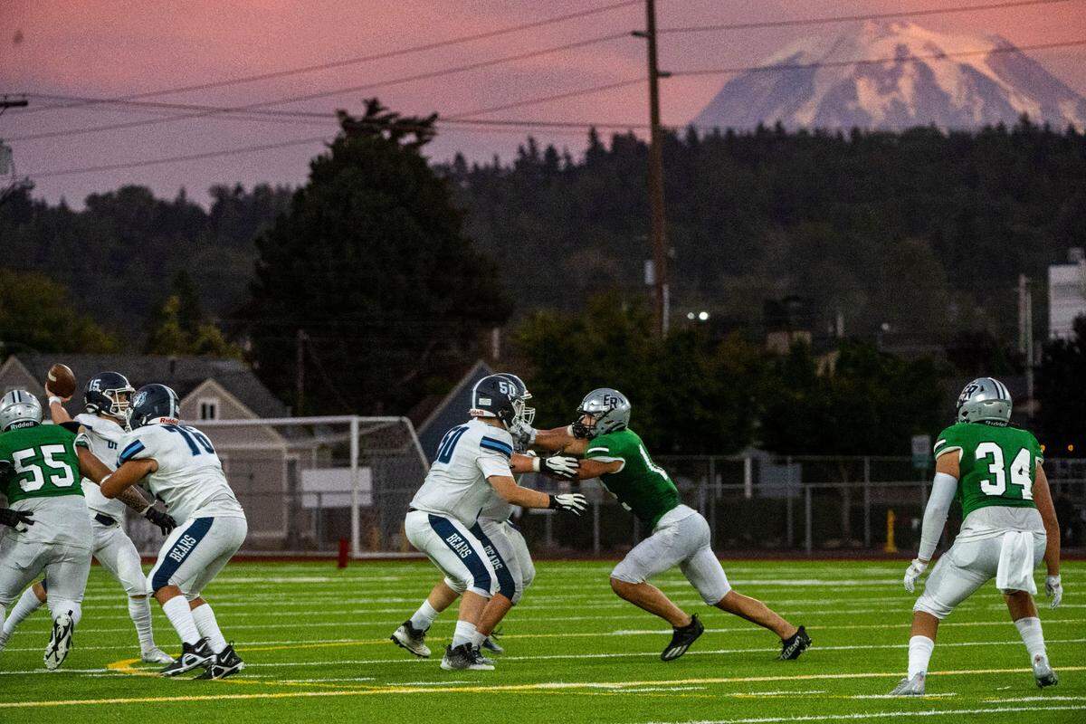 In the background the top of Mt. Rainier is highlighted by the setting sun as Olympia quarterback Gabe Downing attempts a pass during the second quarter of a 4A SPSL game against Emerald Ridge at Sparks Stadium on Thursday, Sept. 8, 2022, in Puyallup, Wash.