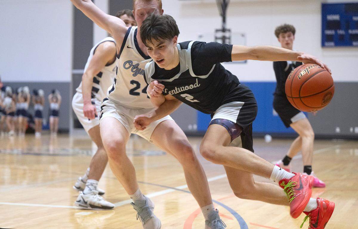 Kentwood’s Brandon Tagle drives the lane against OIympia defender Blake Peterson during Thursday night’s 4A District 3/4 semifinal boys basketball game at Federal Way High School in Federal Way, Washington, on Feb. 15, 2023. Kentwood won the game in overtime, 51-42.
